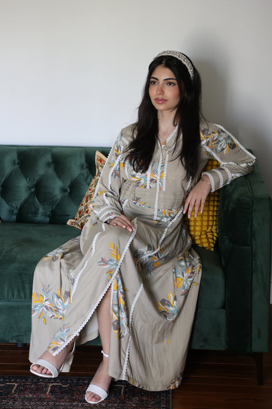 Woman in a embroidered maxi dress sitting on a green couch.